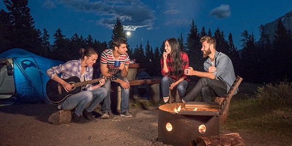 Friends around a picnic table at their campsite.